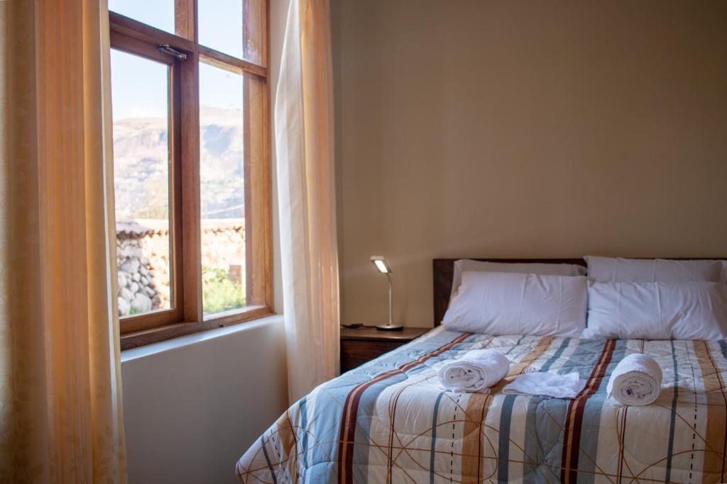 a bedroom with a bed with a window at Allin Illary Eco Hospedaje in Urubamba