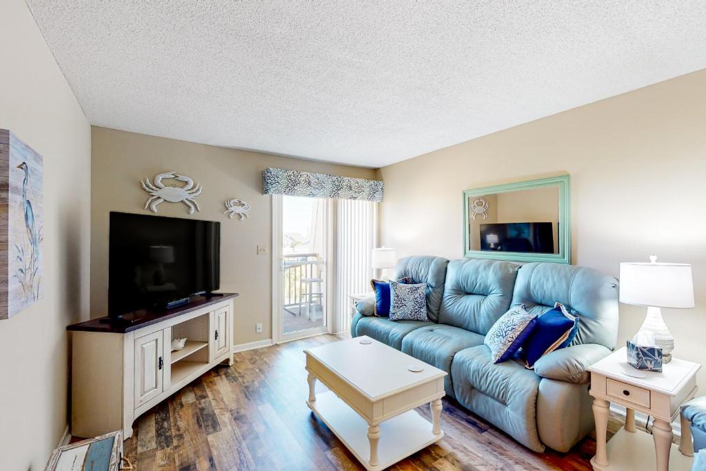 sala de estar con sofá azul y TV en Stay Salty, en Myrtle Beach
