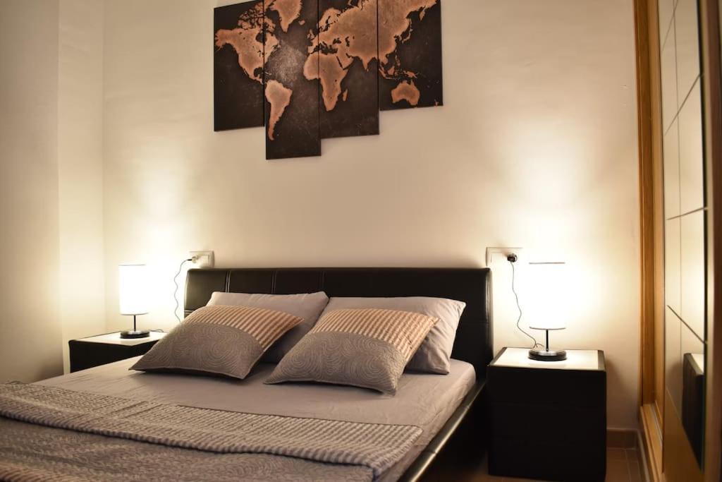 Apartamento Carteya في الجزيرة الخضراء: غرفة نوم بسرير مع مصباحين وخريطة