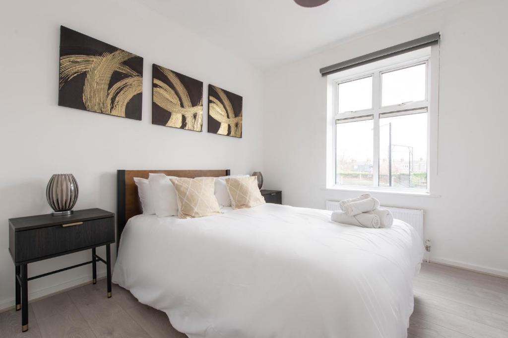 een witte slaapkamer met een groot bed en een raam bij Modern Luxury Apartment by Bow Road Station in Londen