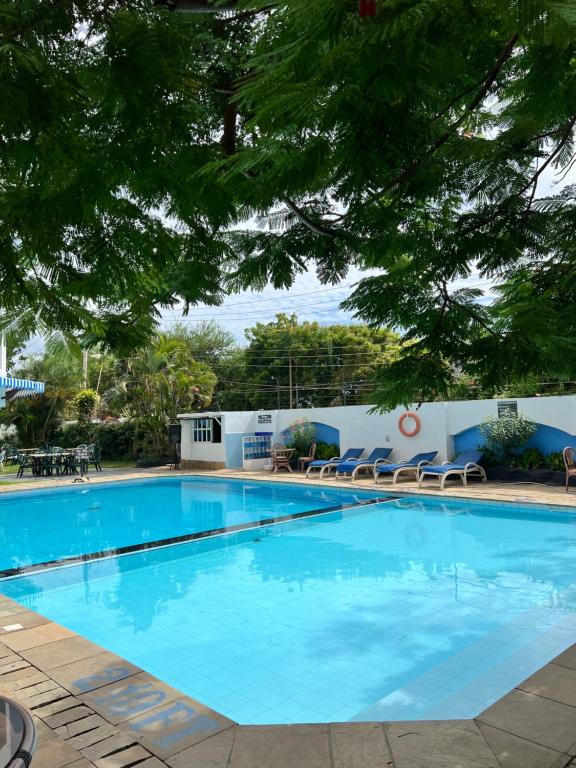 a large blue swimming pool with chairs and a building at Sandy Shores-Nyali, Mombasa in Mombasa