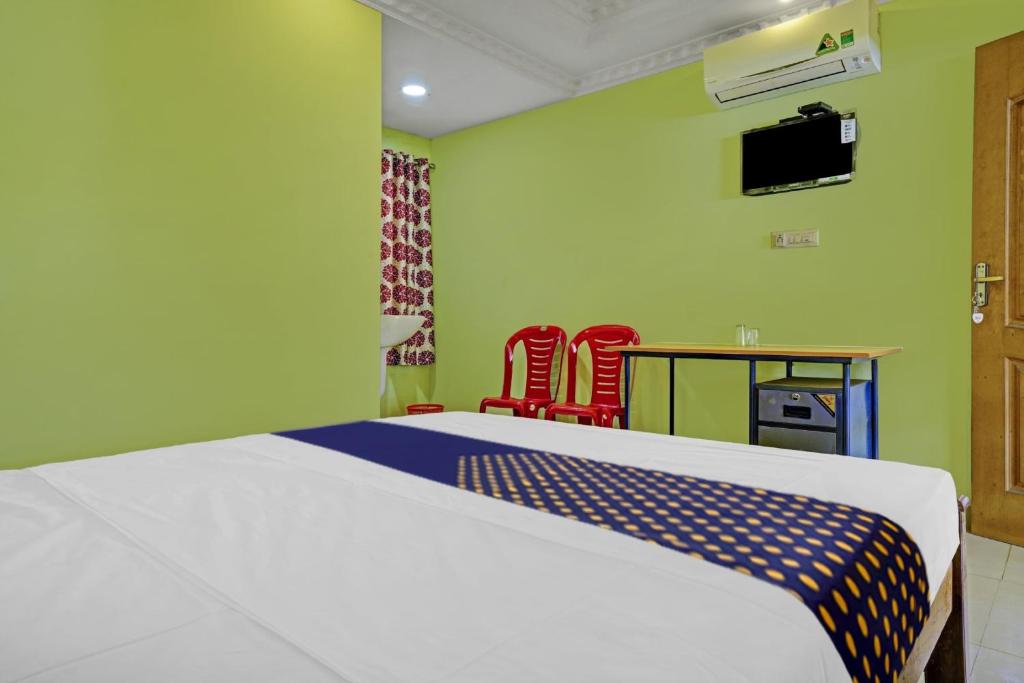 a bedroom with a bed and two red chairs at OYO Hotel SS Residency in Punalūr