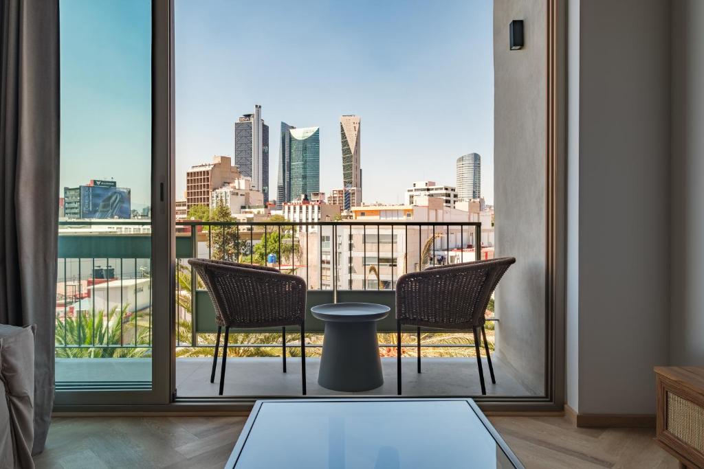 a balcony with two chairs and a view of a city at Casa Cibeles by Lumina in Mexico City