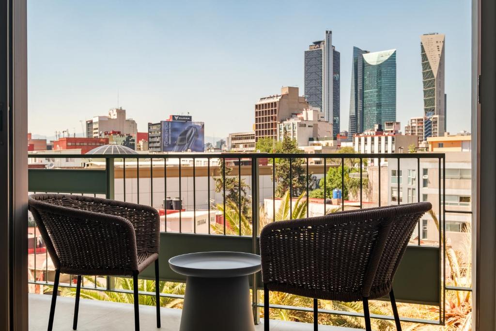 a balcony with two chairs and a table and a city at Casa Cibeles by Lumina in Mexico City