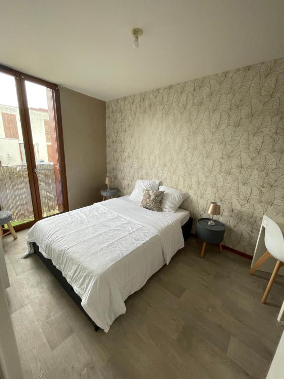 サン・ジャック・ド・ラ・ランドにあるCHARMANT APPARTEMENT AVEC GRANDE CAPACITÉ D’ACCUEILの白い大型ベッドと壁が備わるベッドルーム1室が備わります。