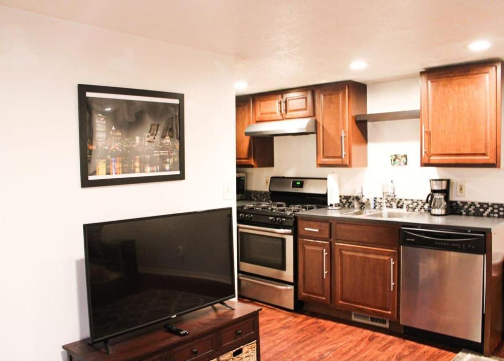 a kitchen with wooden cabinets and a flat screen tv at 1 Bed Apt - Amazing Location 1 Block to Carson St in Pittsburgh