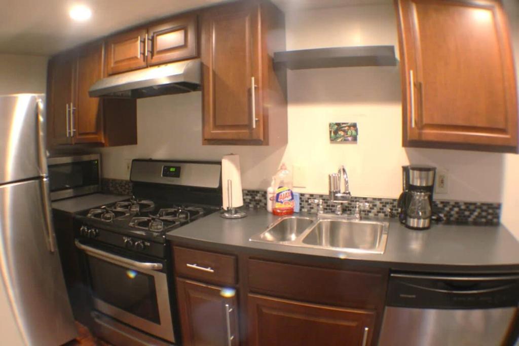 a kitchen with wooden cabinets and a stainless steel sink at 1 Bed Apt - Amazing Location 1 Block to Carson St in Pittsburgh