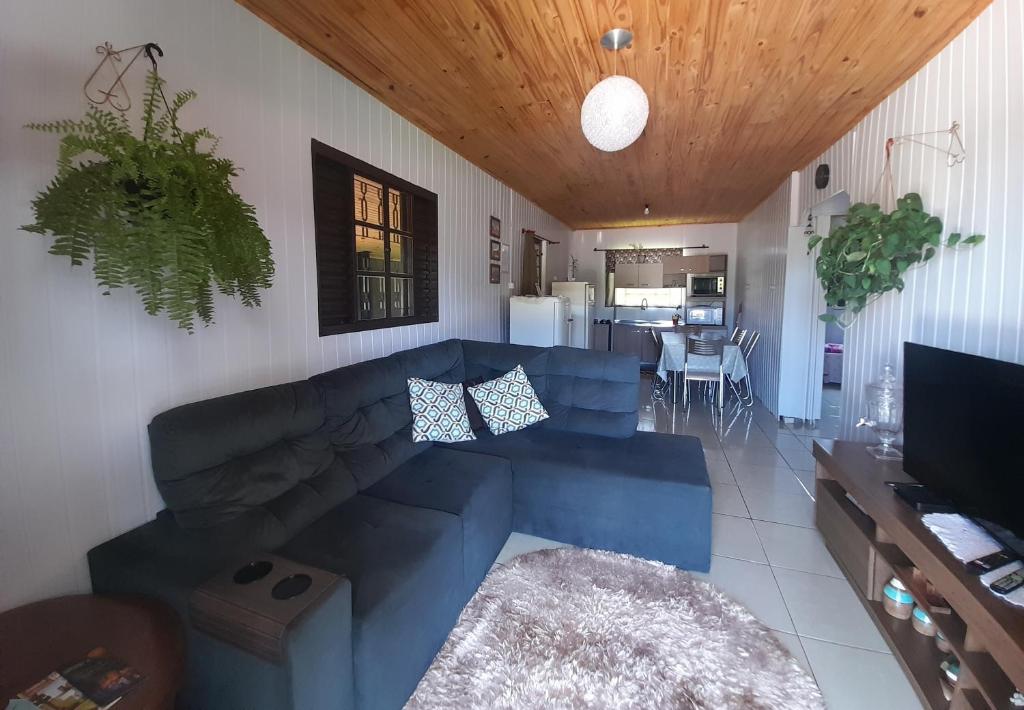 a living room with a blue couch and a kitchen at Casa Encanto in São Miguel das Missões