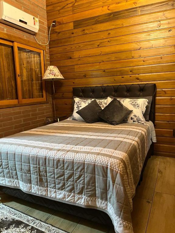 um quarto com uma cama numa parede de madeira em Cabana Bela Vista em Santa Maria do Erval