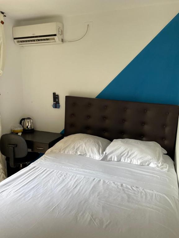 a bed with two white pillows and a blue wall at Habitación de descanso con aire acondicionado in Villavicencio