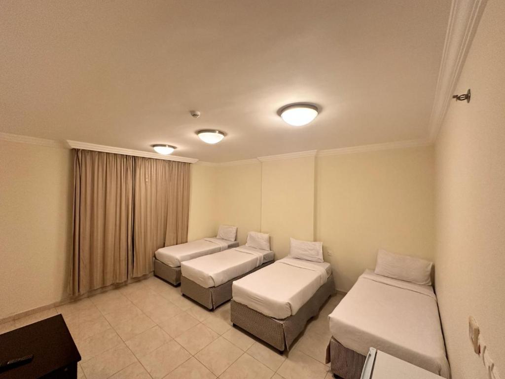 a hospital room with three beds and a table at ALBILAD ROYA HOTEL in Makkah