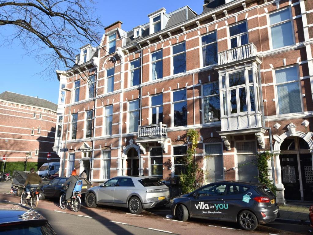 een groep auto's geparkeerd voor een gebouw bij De Kleine Regentes in Den Haag