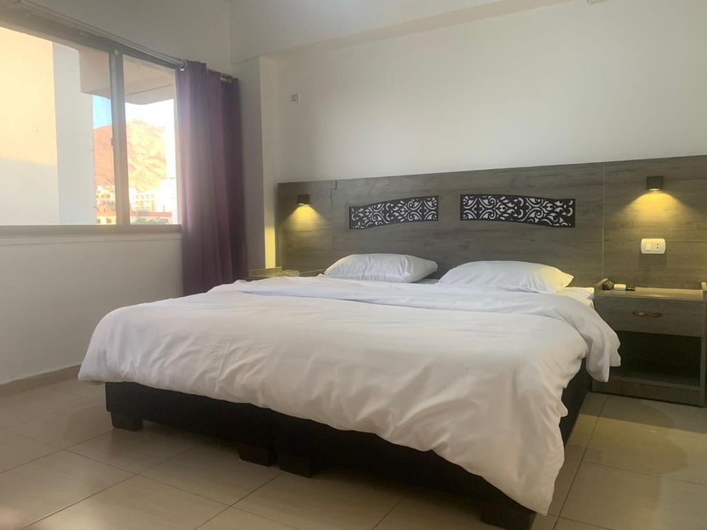 a large white bed in a bedroom with a window at Best hotel aqaba in Aqaba