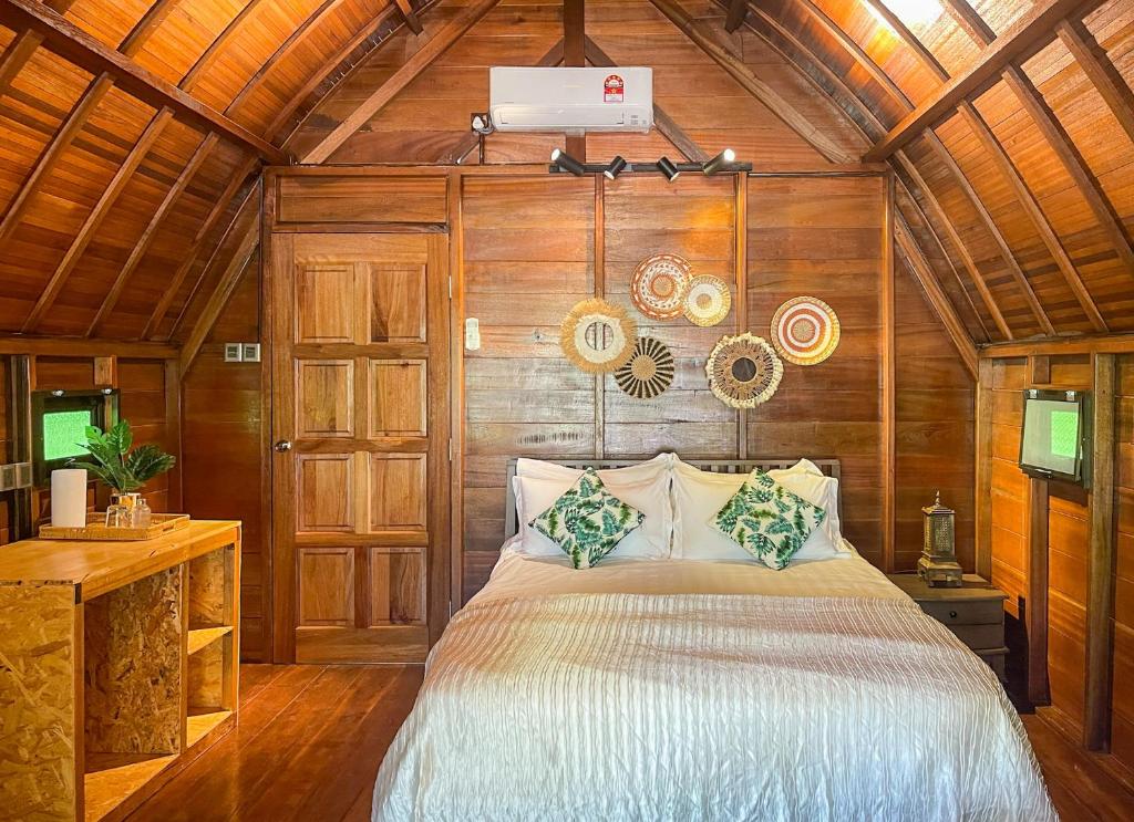 1 dormitorio con 1 cama y pared de madera en Golden Chenang Village en Pantai Cenang