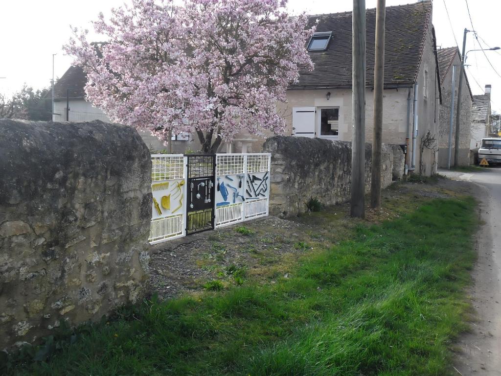 einen Steinzaun und einen Baum mit rosa Blumen in der Unterkunft Gîte Saint-Hilaire-sur-Benaize, 2 pièces, 3 personnes - FR-1-591-575 in Saint-Hilaire-sur-Bénaize
