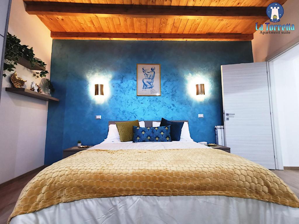 een slaapkamer met een groot bed met een blauwe muur bij LA TORRETTA apartment suite in Anagni