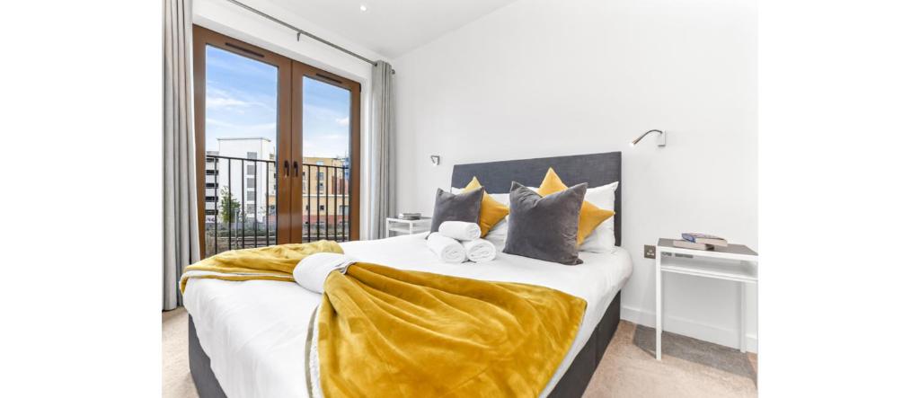 um quarto com uma cama grande com lençóis e almofadas amarelos em Metropolitan Luxury: Chic 2BR Flat in St. Albans em Saint Albans
