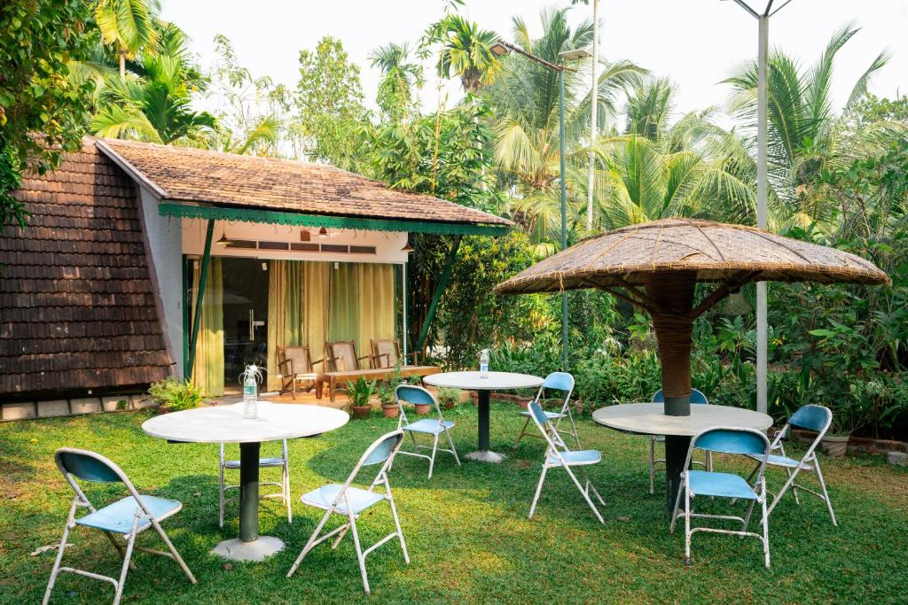 2 tables et chaises avec parasols dans la cour dans l'établissement Garggi Kumarakom Village Homestay, à Kumarakom