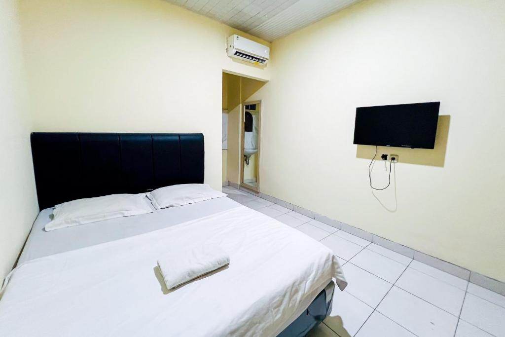 1 dormitorio con 1 cama y TV en la pared en Wisma Berkat Mitra RedDoorz, en Yakarta
