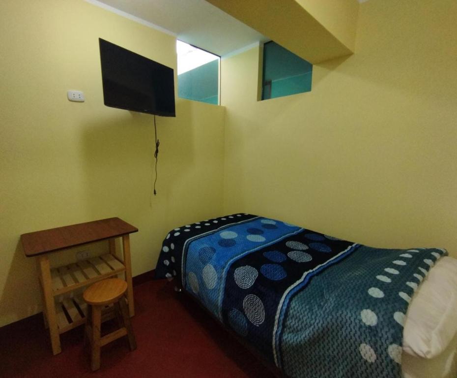 a bedroom with a bed and a desk and a television at Hospedaje LOS OLIVOS in Ayacucho