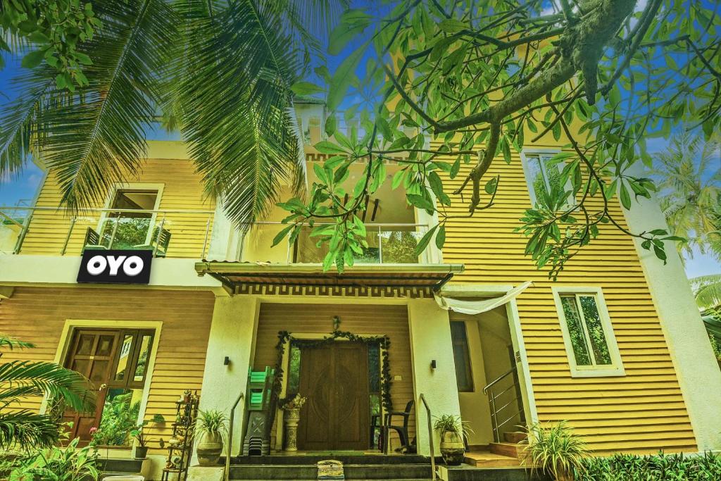 une maison jaune avec un panneau à l'avant dans l'établissement OYO Flagship Peppy Guest House, à Calangute