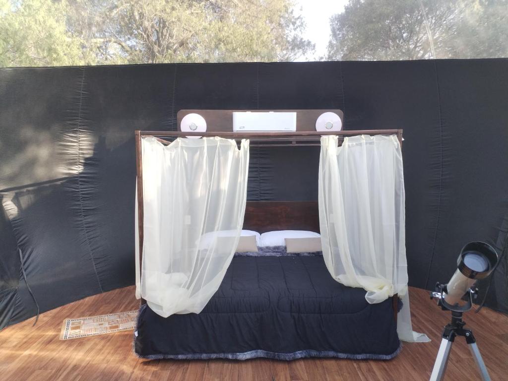 a bed in a tent with curtains and a camera at MEYAHUALLI GLAMPING in Huasca de Ocampo