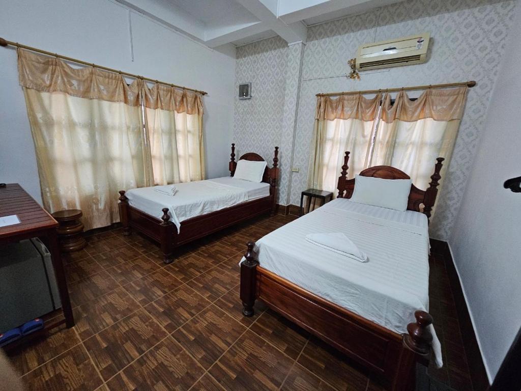 a bedroom with two beds and a tv in it at Maylayguesthouse1 in Vang Vieng