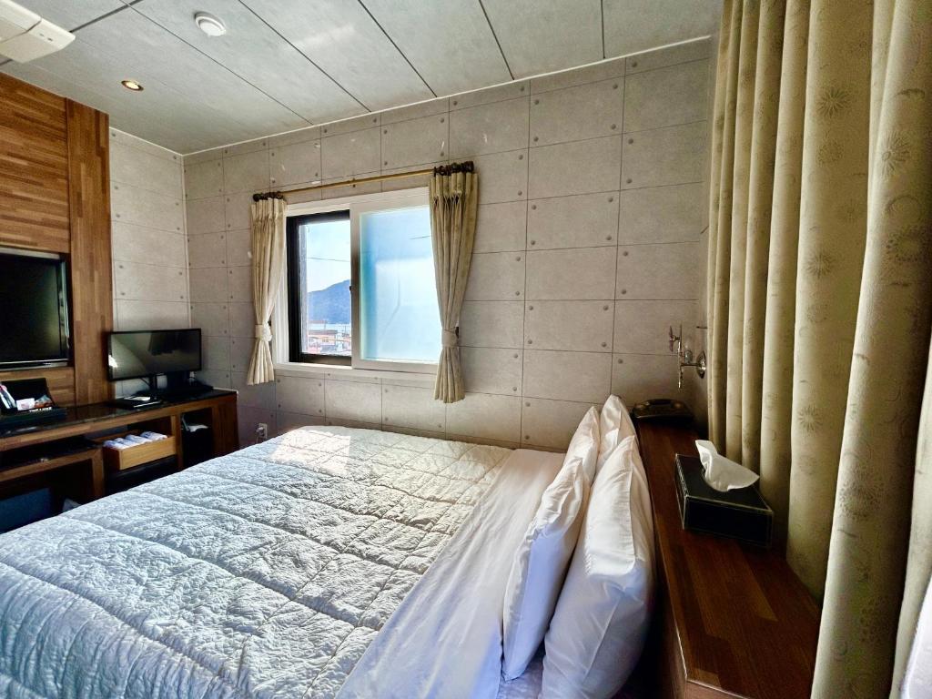 a bedroom with a bed and a desk and a window at Ocean hotel the Luxe in Geoje