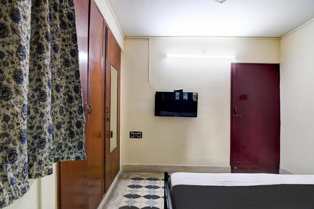 a room with a bed and a red door and a tv at OYO Simplex Guest House Behala in Kolkata
