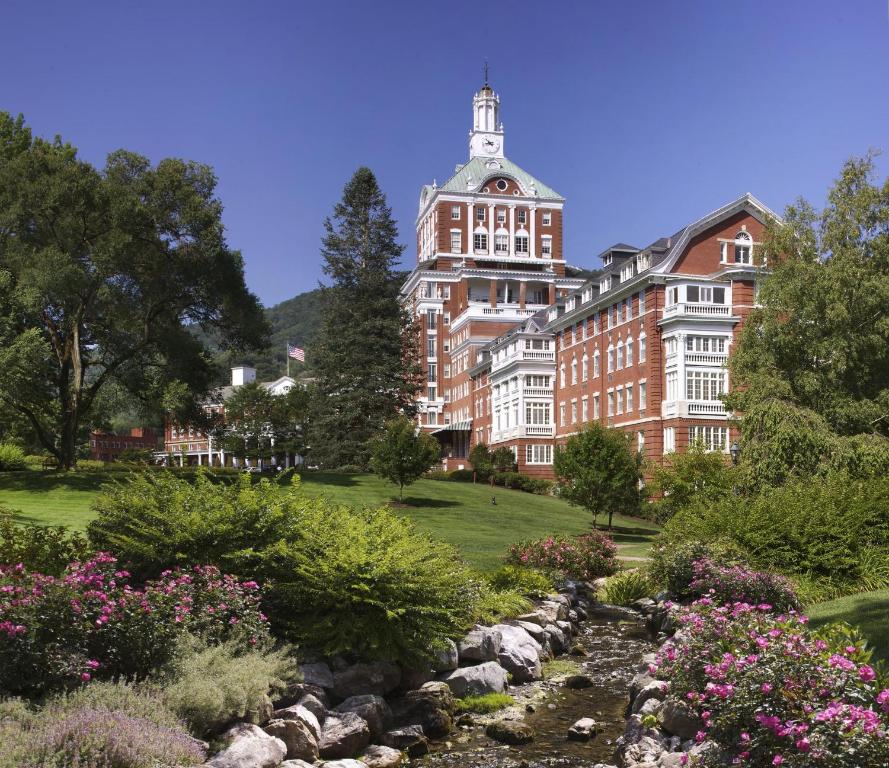 a large red brick building with a garden in front at The Omni Homestead Resort in Hot Springs
