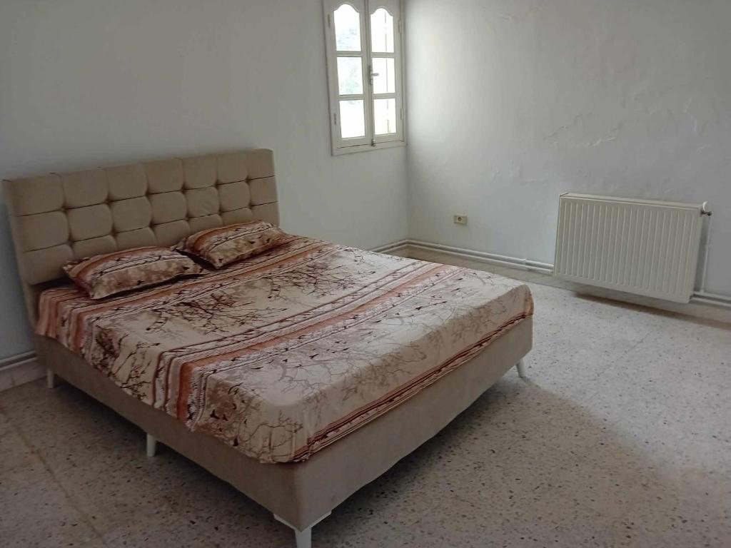 uma cama num quarto branco com uma janela em Joli Appartment A Zitouna 2 em Port El Kantaoui