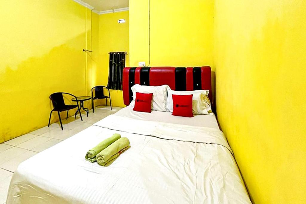 een slaapkamer met een bed met rode en gele muren bij Hotel Alam Lestari RedPartner in Palembang