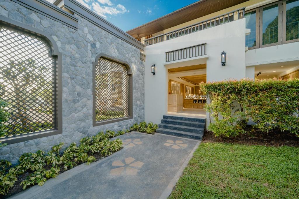 an exterior view of a home with a stone wall at Bhu Nga Thani Resort & Villas Railay in Railay Beach