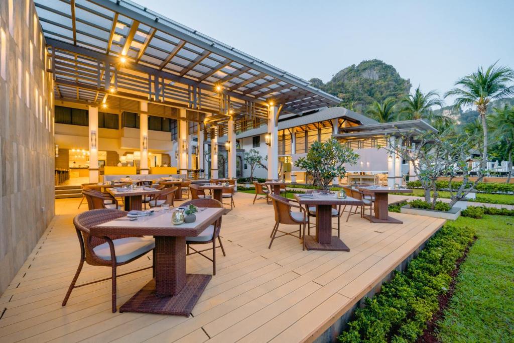 a patio with tables and chairs and a building at Bhu Nga Thani Resort & Villas Railay in Railay Beach