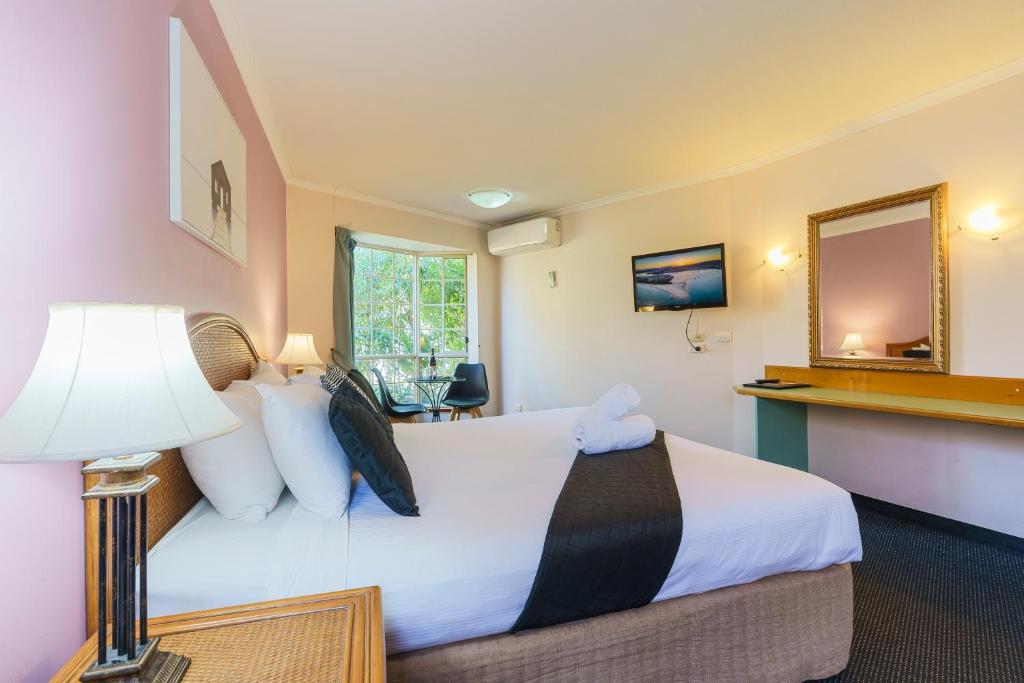a hotel room with a bed and a mirror at Sapphire Waters Motor Inn in Merimbula