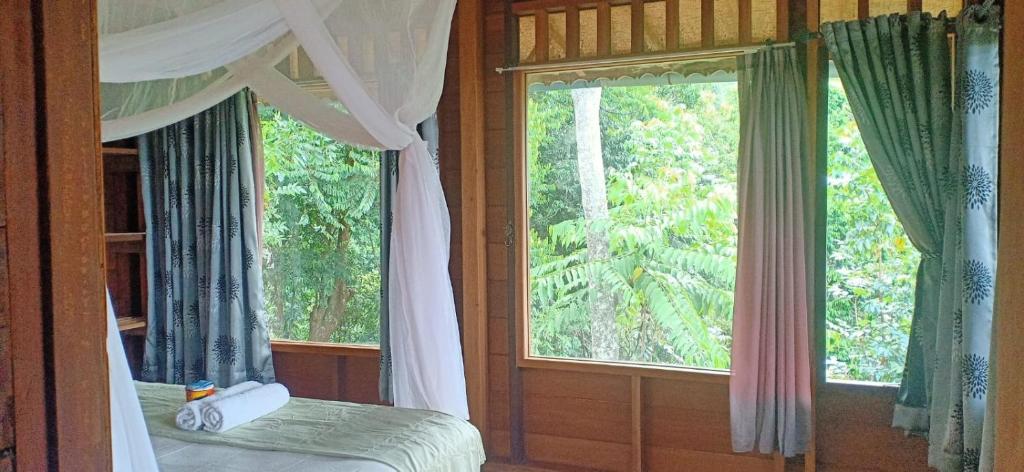 a bedroom with a bed and a large window at On The Rocks Bungalows, Restaurant and Jungle Trekking Tours in Bukit Lawang
