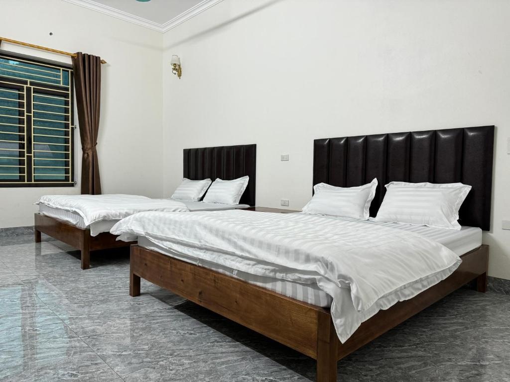 2 Betten in einem Zimmer mit weißer Bettwäsche und Kissen in der Unterkunft Hotel Minh Thắng in Phủ Nho Quan