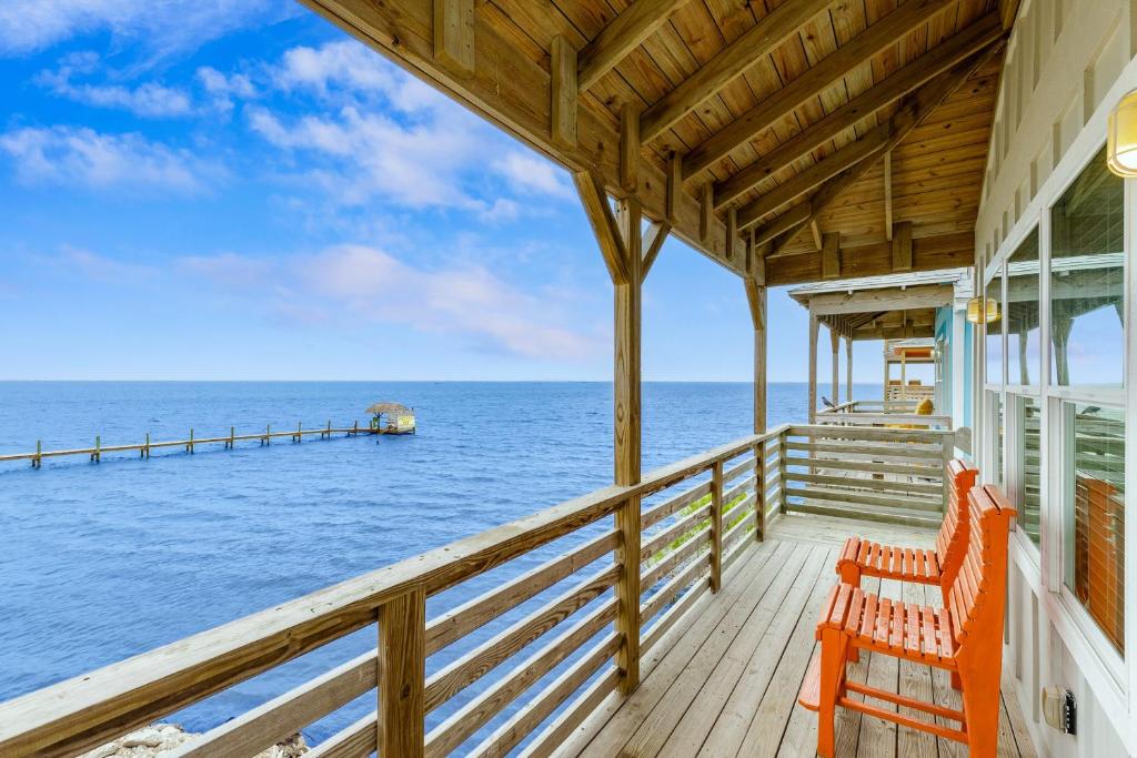 une terrasse avec deux chaises oranges et une jetée dans l'établissement Fins and Feathers by AvantStay Waterfront Views, à Île Padre