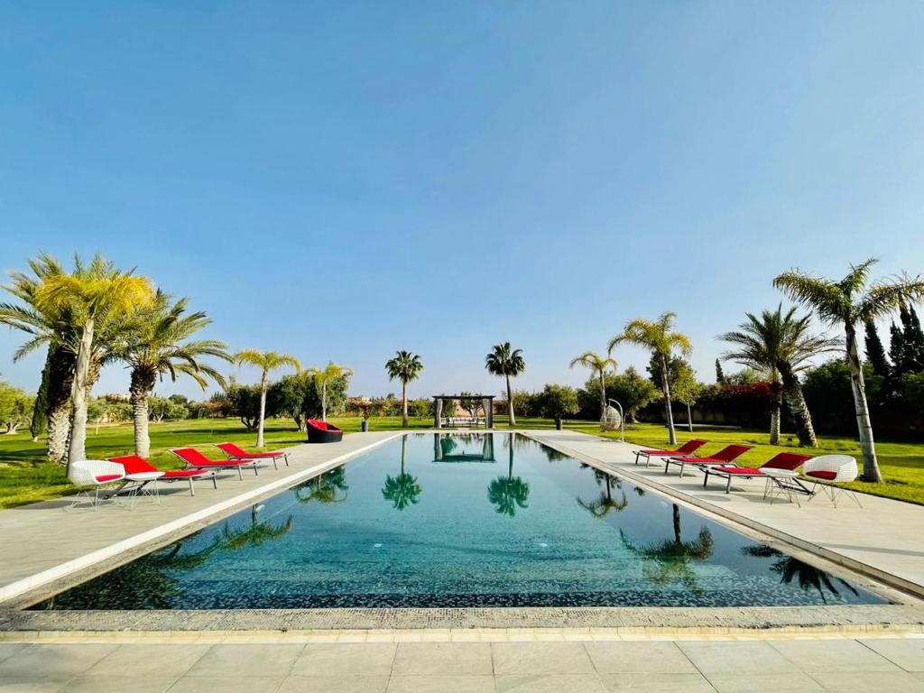 a swimming pool with red chairs and palm trees at Villa Dar El Hna in Marrakesh