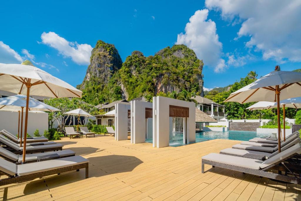 a resort with a pool with chairs and umbrellas at Bhu Nga Thani Resort & Villas Railay in Railay Beach