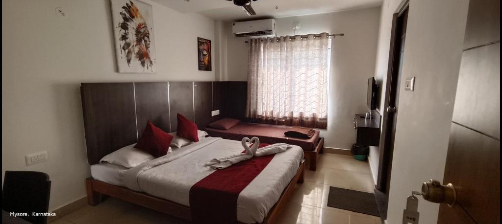 een slaapkamer met een bed met rode kussens en een raam bij Quince mysore in Mysore