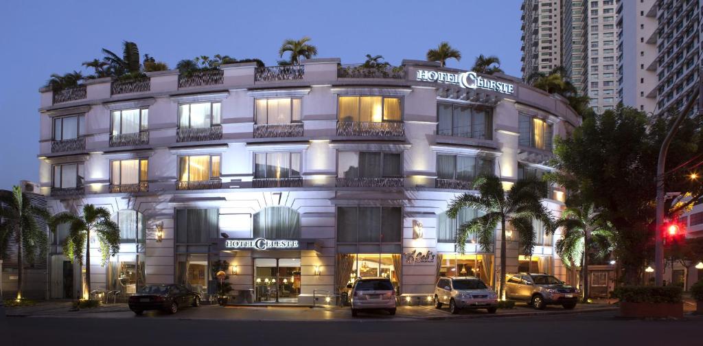 Biały budynek z samochodami zaparkowanymi przed nim w obiekcie Hotel Celeste Makati w mieście Manila