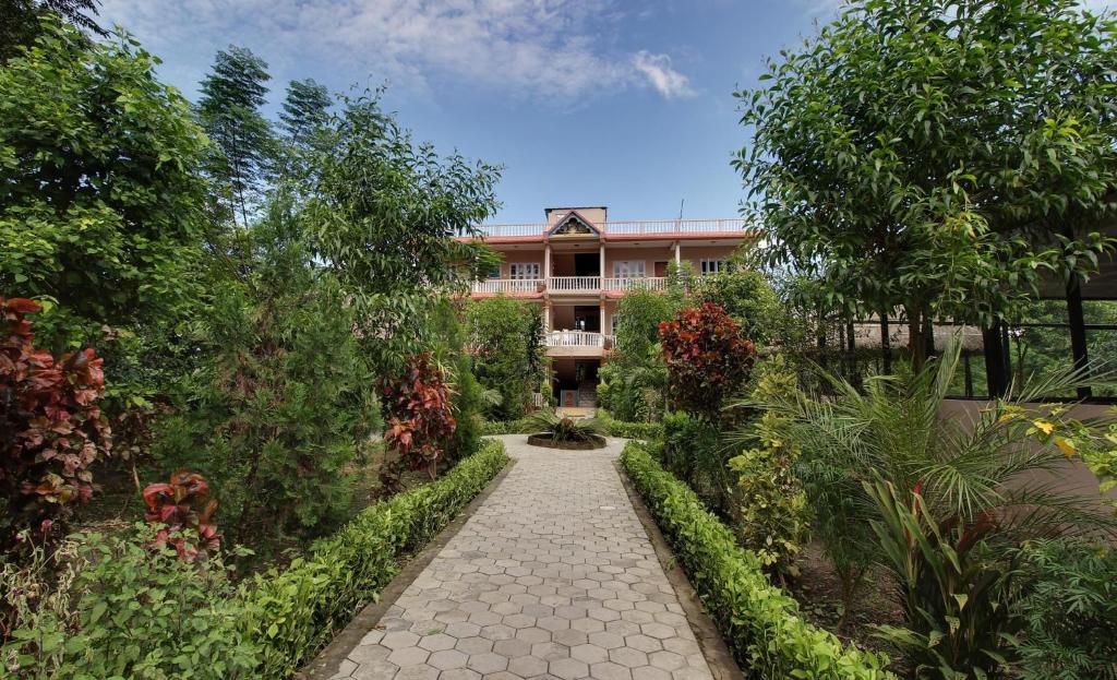 a building with a walkway in front of a garden at Eco Adventure Resort in Sauraha