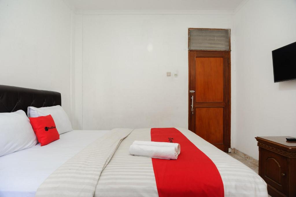 a bedroom with a bed with a red stripe on it at RedDoorz syariah near AEON Mall Tanjung Barat in Jakarta