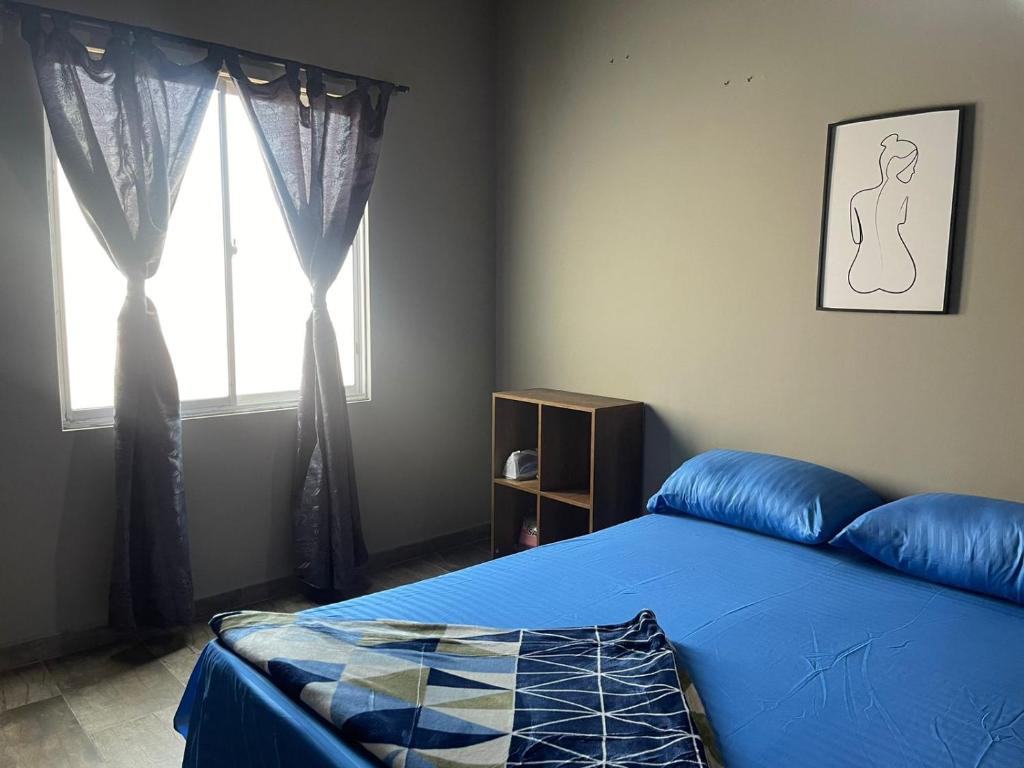 Un dormitorio con una cama azul y una ventana en MAGICO APARTA ESTUDIO BELEN FATIMA, en Medellín