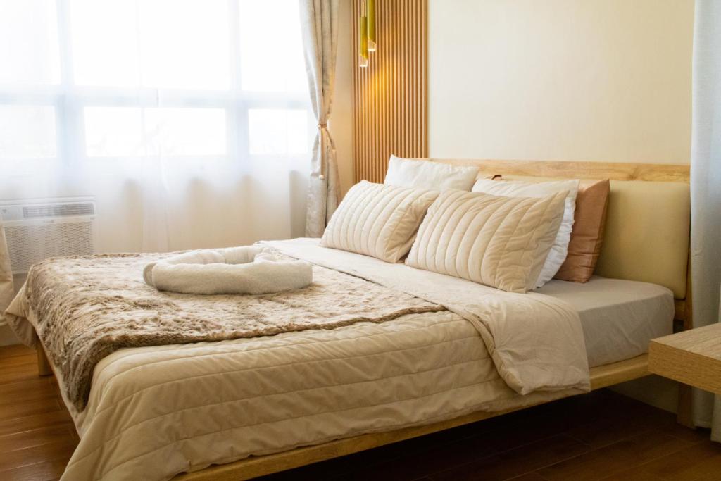 Un dormitorio con una cama con almohadas blancas y una ventana en Micairan Suite, en Davao City