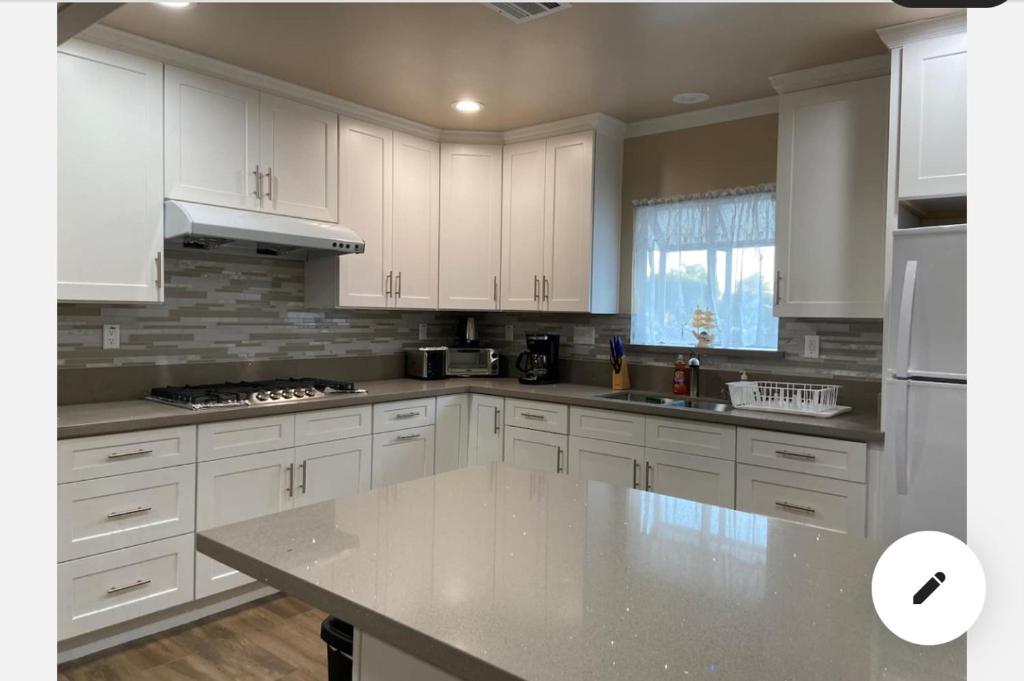 a kitchen with white cabinets and a counter top at New! Cozy Gated 3BR, 2BA Vacation Home in Rosemead