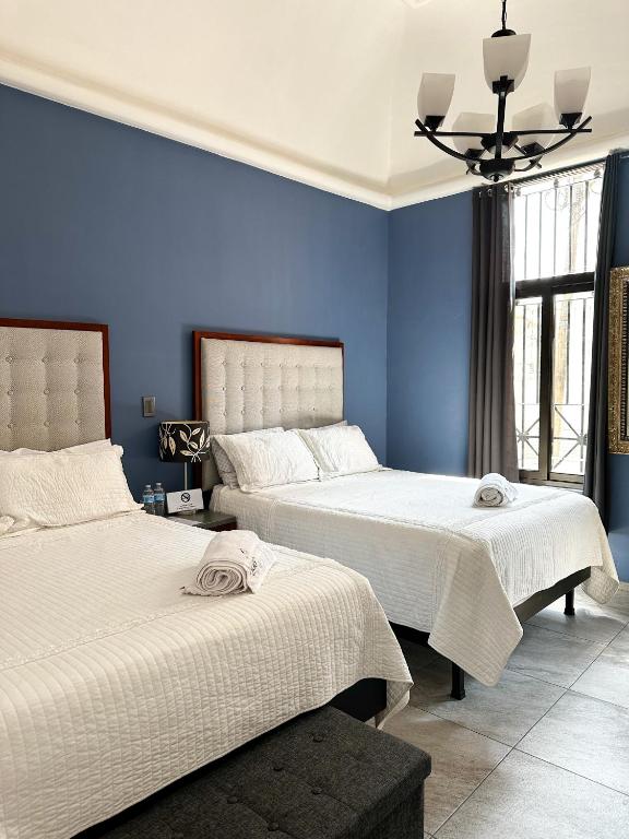 two beds in a room with blue walls at Hotel Asís in San Juan de los Lagos