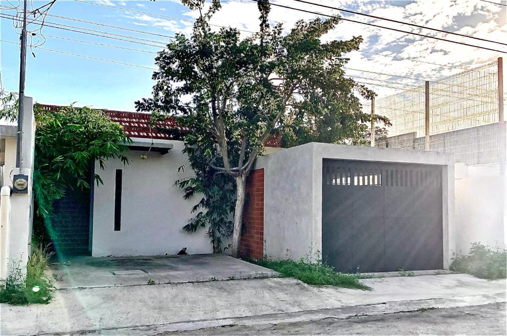 een witte garage met een hek en een boom bij Casa Esmeralda in Petkanché