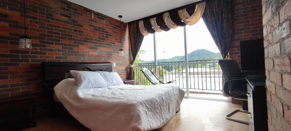ein Schlafzimmer mit einem Bett und einem großen Fenster in der Unterkunft Apartamento en Retiro in El Retiro